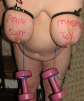 An Masters Schmerz Schlampe hängen Gewichte an den Brüsten