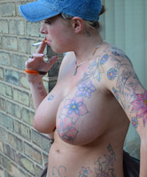 Nackte ist tätowiert und raucht eine Zigarette